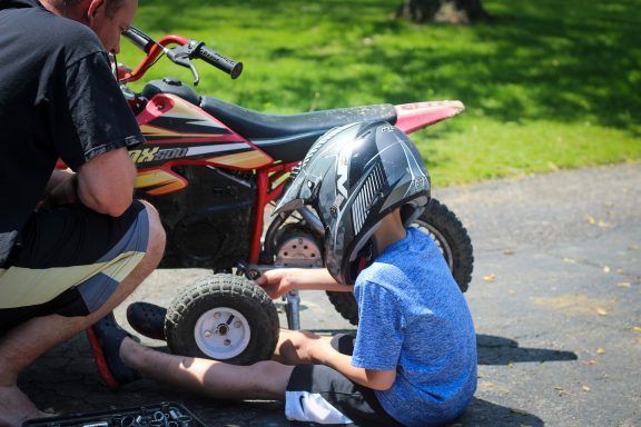 child working on dirt bike with father