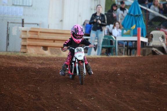 young child riding motocross dirt bike with pink protective gear